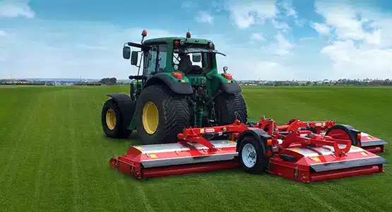 Turf Farm & Management's red mower is attached to the tractor mowing the field.